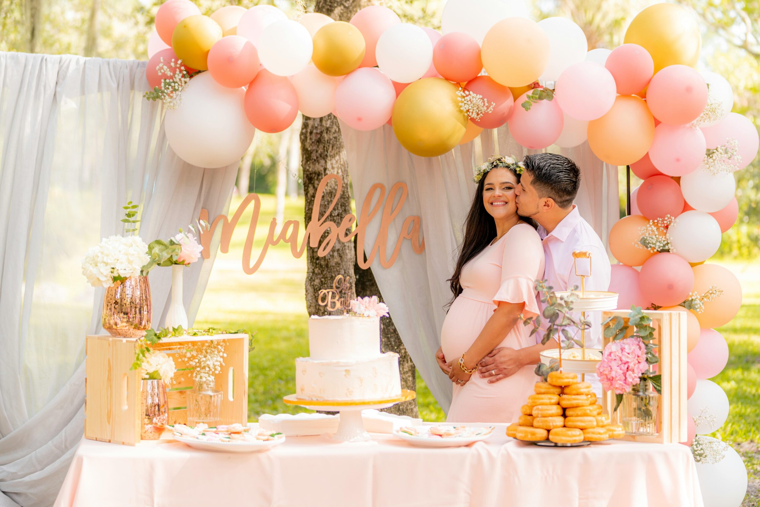 Joyful couple celebrating a baby shower with a lovely dessert table and pastel decor.